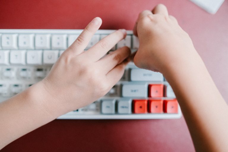 persons left hand on red and white computer keyboard