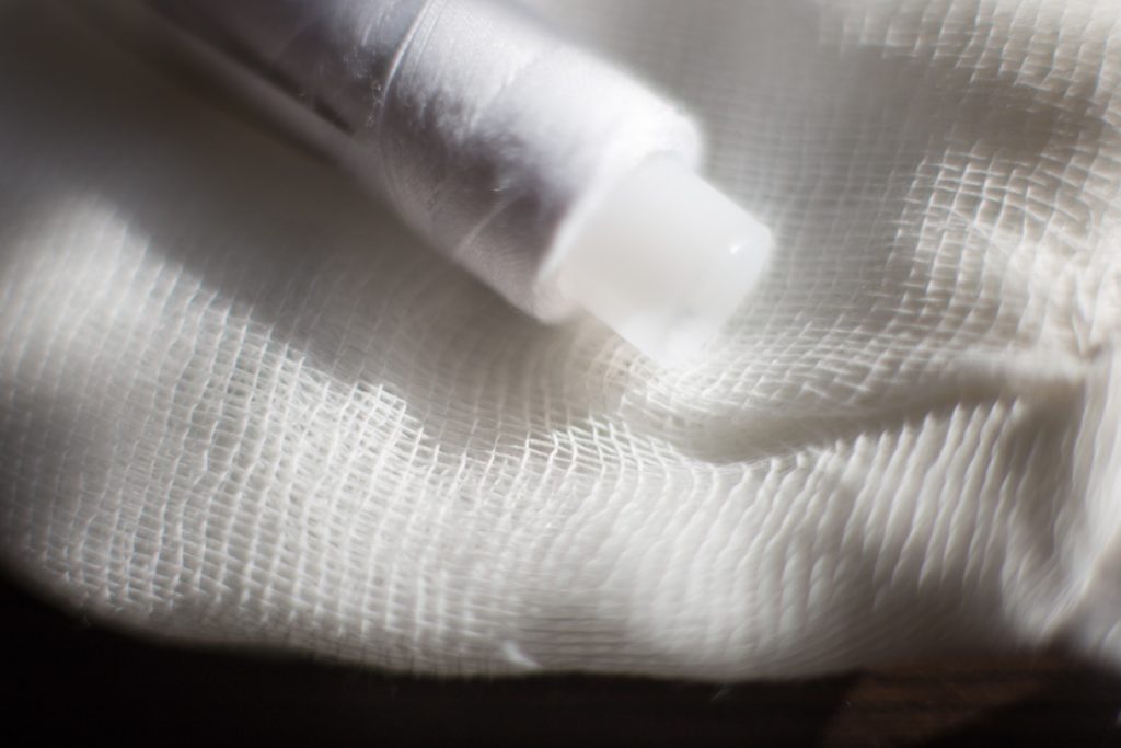 white plastic bottle on white textile