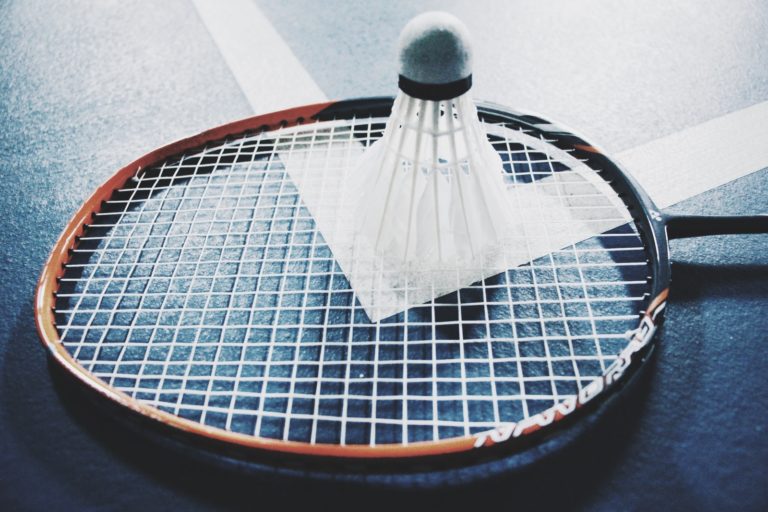 white shuttlecock on brown and black badminton racket placed on floor